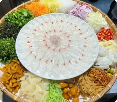顺德鱼生薄切鱼片摆盘，四周环绕葱姜丝、洋葱、香菜、炸花生等配料