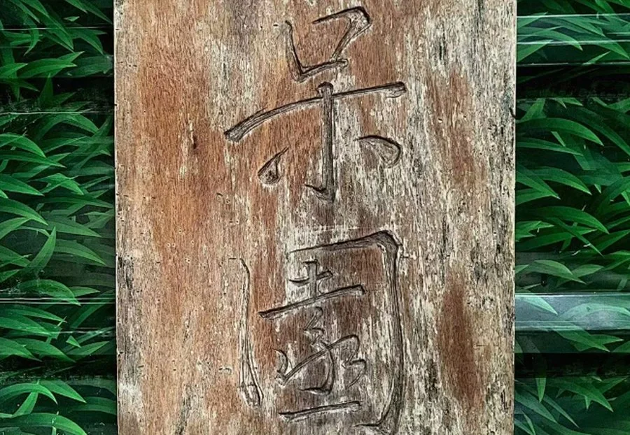 呆园的木牌招牌,毛笔手书的“呆园”二字挂在园门绿植之间