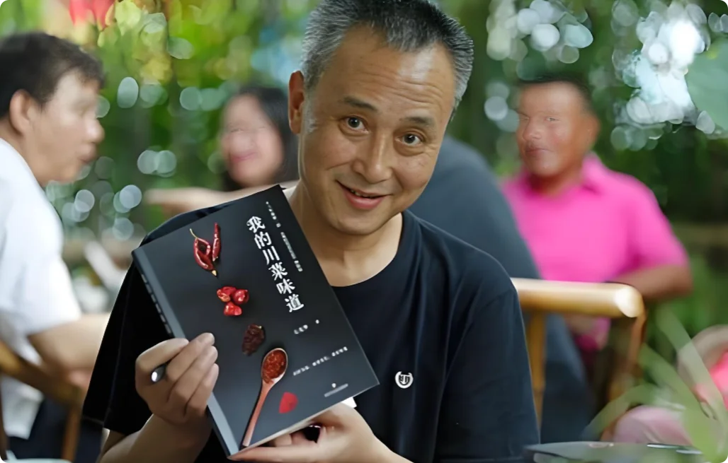 石光华手持著作《我的川菜味道》，黑色封面上辣椒与木勺图案，笑容亲切