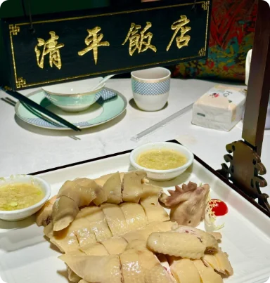 清平饭店招牌前的一盘白切鸡，鸡皮光洁，配姜葱蘸料