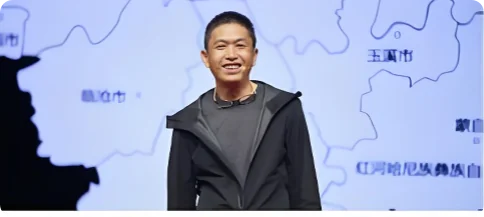杨一军（敢于胡乱）站在云南地图前，笑容质朴，目光笃定